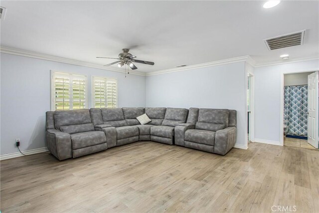 living room featuring light wood-style floors, crown molding, a ceiling fan, visible vents, and baseboards