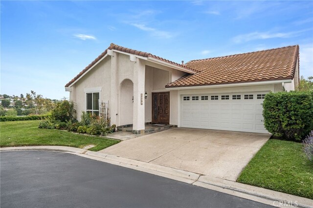 mediterranean / spanish house with stucco siding, a tiled roof, a garage, a front yard, and concrete driveway