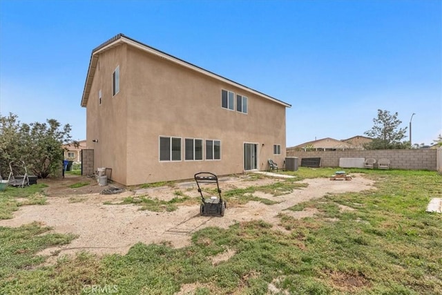 back of house featuring fence, central AC, and stucco siding