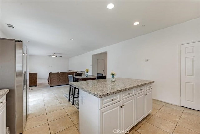 kitchen with stainless steel fridge with ice dispenser, white cabinets, a center island, visible vents, and light tile patterned flooring