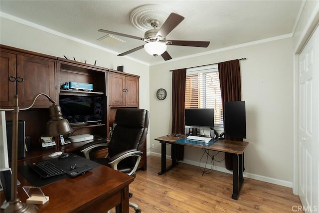 office space featuring light wood-style flooring, ceiling fan, baseboards, visible vents, and crown molding