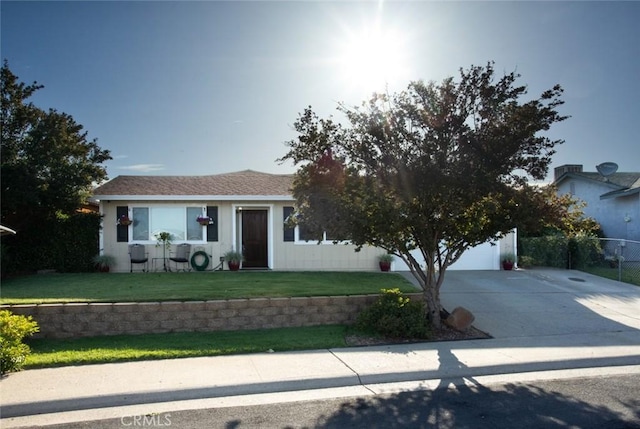 view of front of house featuring fence, concrete driveway, a front lawn, and a garage