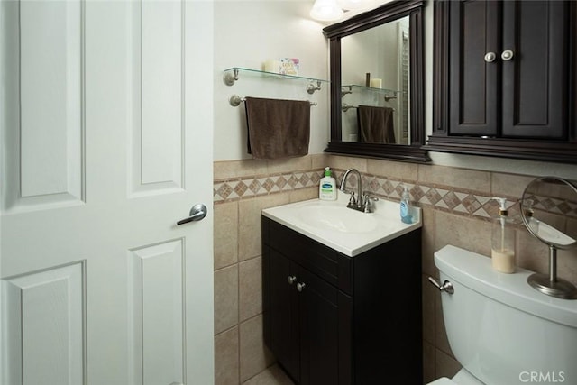 bathroom featuring vanity, toilet, and tile walls