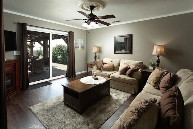 living room with baseboards, ornamental molding, dark wood-style floors, visible vents, and a ceiling fan
