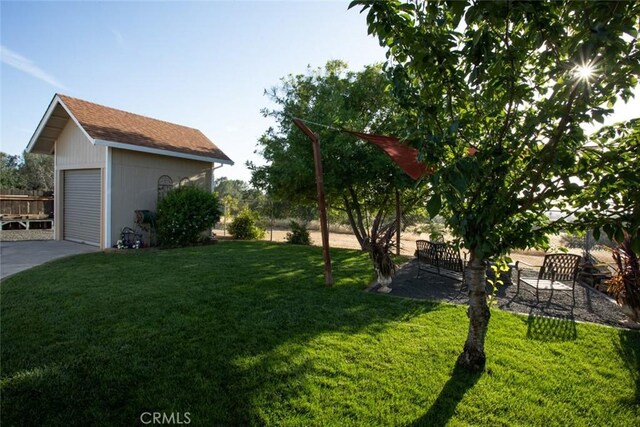 view of yard featuring an outbuilding, driveway, a garage, and fence