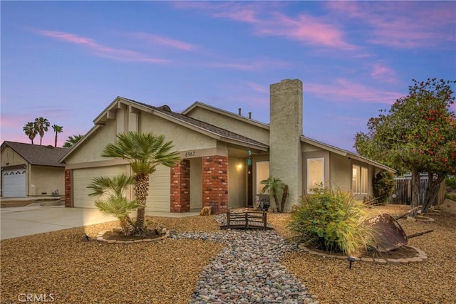 6967 Mountain Ave, Highland, CA 92346 - single story home with brick siding, a garage, stucco siding, a chimney, and concrete driveway