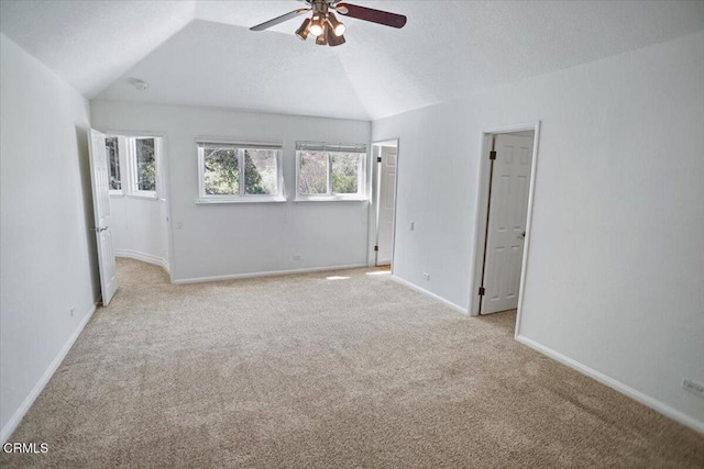unfurnished room with ceiling fan, vaulted ceiling, light carpet, and baseboards