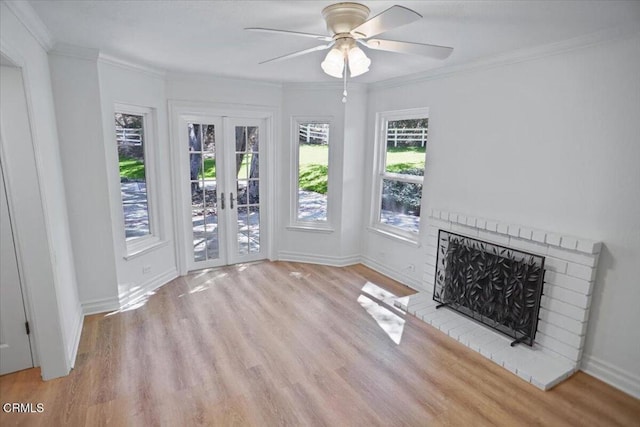 unfurnished living room with a brick fireplace, a ceiling fan, wood finished floors, and french doors