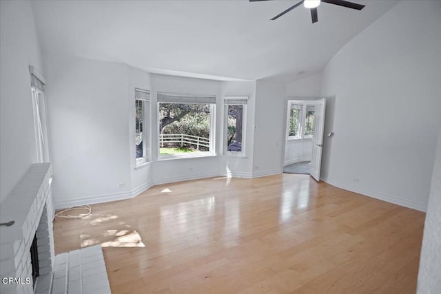 unfurnished living room with light wood-style flooring, ceiling fan, a fireplace, baseboards, and lofted ceiling