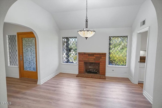 unfurnished living room featuring visible vents, a wealth of natural light, light wood finished floors, and vaulted ceiling