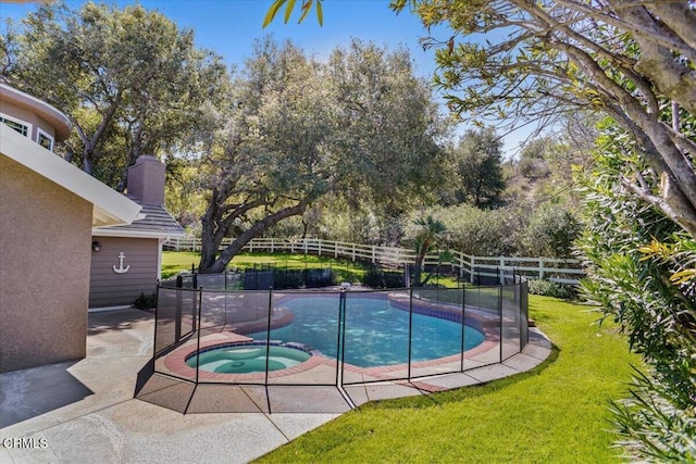 view of pool with a pool with connected hot tub, fence, and a yard