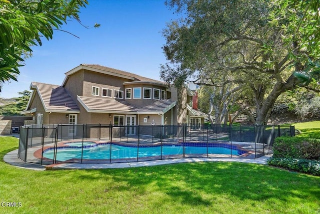 view of swimming pool featuring a pool with connected hot tub, fence, and a yard