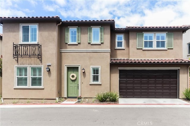 view of property with stucco siding, concrete driveway, an attached garage, and a tile roof