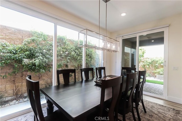 dining space featuring a healthy amount of sunlight, baseboards, wood finished floors, and a notable chandelier