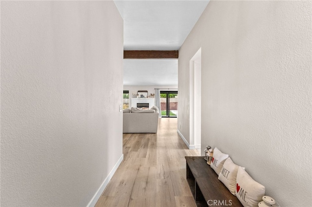 hallway featuring light wood finished floors and baseboards