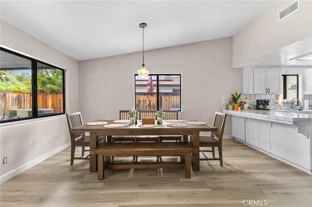 dining area featuring lofted ceiling, visible vents, light wood-style flooring, and baseboards