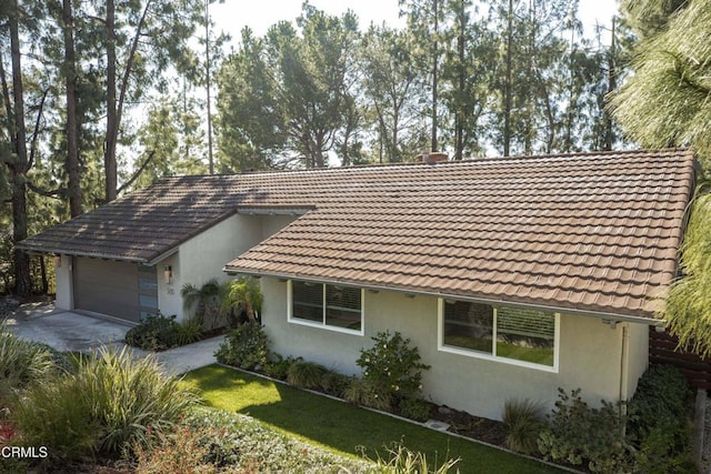 single story home featuring stucco siding, concrete driveway, an attached garage, and a tile roof