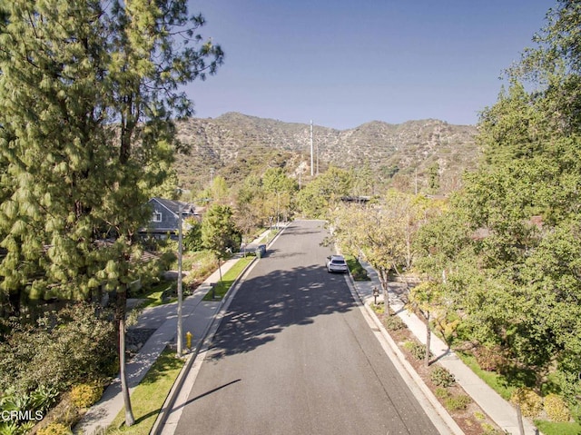view of road featuring curbs, sidewalks, and a mountain view