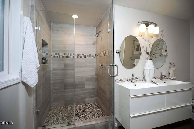 full bath featuring a stall shower, double vanity, and a sink