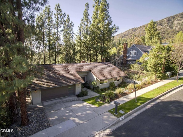 view of front of home with stucco siding, a chimney, concrete driveway, and a garage