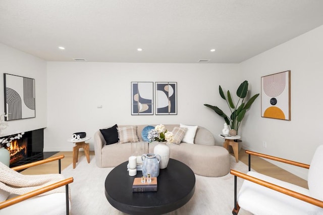 living area featuring visible vents, recessed lighting, and a lit fireplace