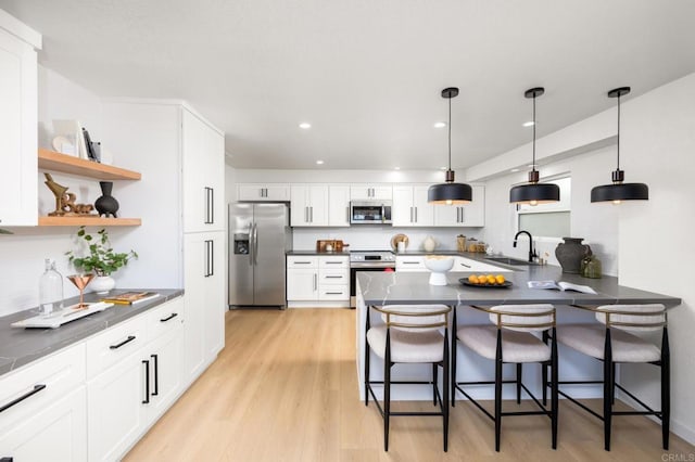 kitchen featuring open shelves, stainless steel appliances, dark countertops, and a sink