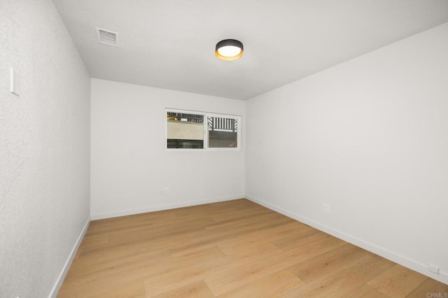 spare room with baseboards, visible vents, and light wood-style flooring