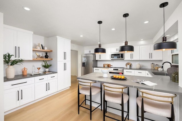 kitchen featuring a sink, stainless steel appliances, open shelves, a peninsula, and dark countertops