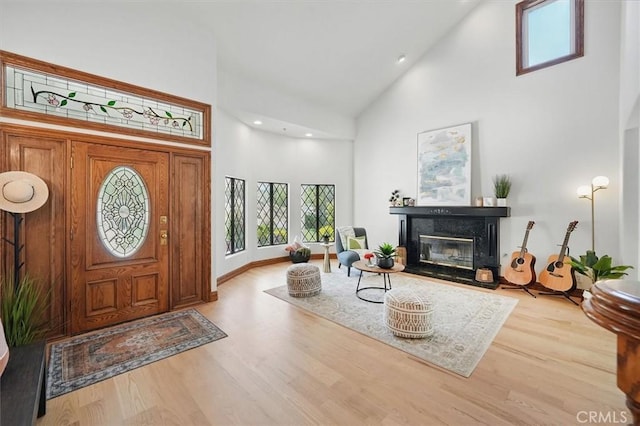 foyer entrance featuring high vaulted ceiling, wood finished floors, a high end fireplace, and recessed lighting