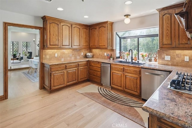 kitchen featuring brown cabinets, a sink, appliances with stainless steel finishes, and a wealth of natural light
