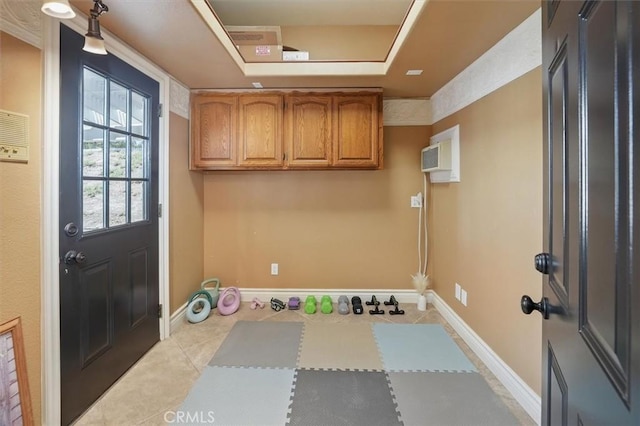 interior space with light tile patterned flooring, a tray ceiling, and baseboards