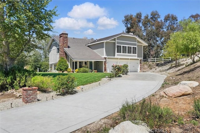 view of front facade featuring driveway, a chimney, a front yard, an attached garage, and fence