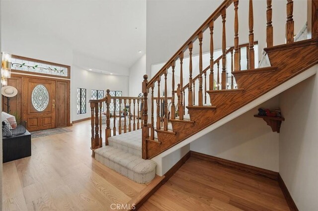 entrance foyer with a high ceiling, stairs, wood finished floors, and baseboards