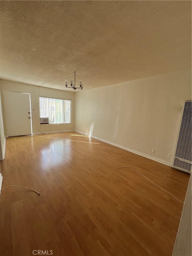1548 N Alexandria Ave, Los Angeles, CA 90027 - unfurnished living room with a heating unit, a chandelier, a textured ceiling, wood finished floors, and baseboards