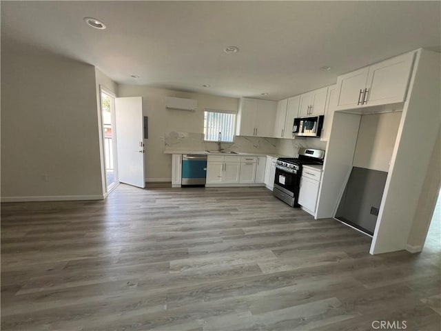 1548 N Alexandria Ave, Los Angeles, CA 90027 - kitchen featuring appliances with stainless steel finishes, a sink, an AC wall unit, white cabinets, and decorative backsplash