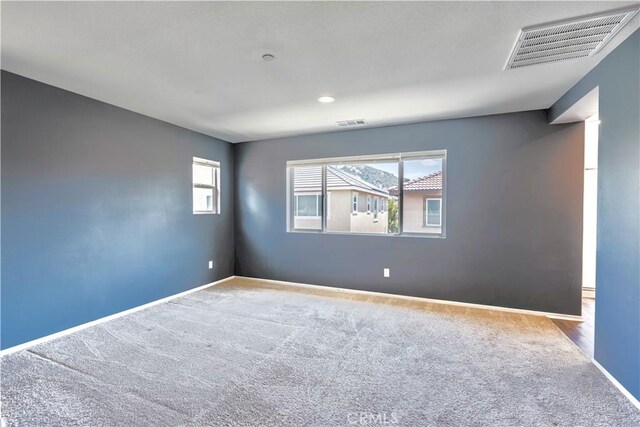carpeted spare room with visible vents and baseboards