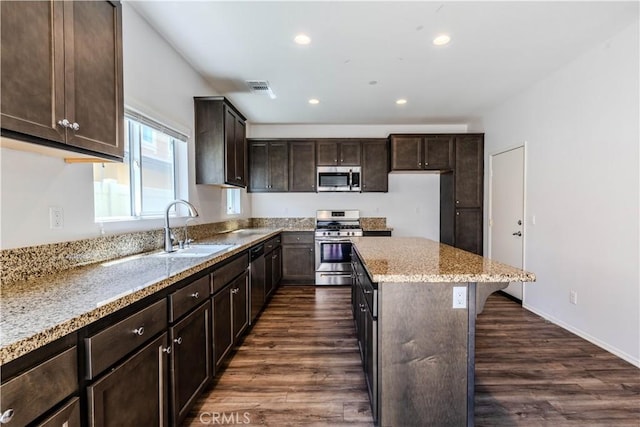 kitchen with a sink, a center island, dark brown cabinetry, visible vents, and appliances with stainless steel finishes