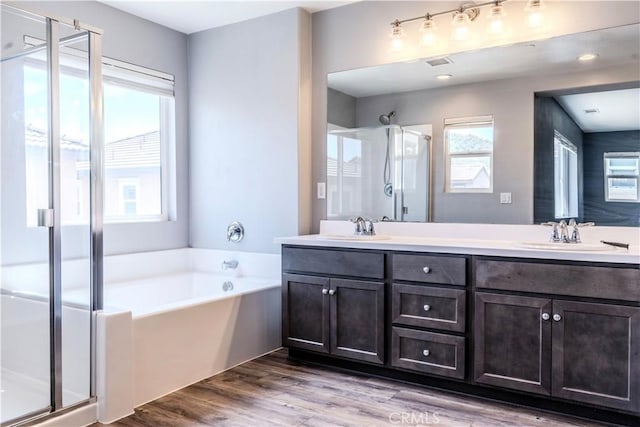 bathroom featuring a stall shower, double vanity, a bath, and a sink