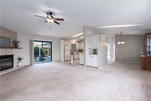 unfurnished living room with a glass covered fireplace, light carpet, baseboards, and ceiling fan with notable chandelier