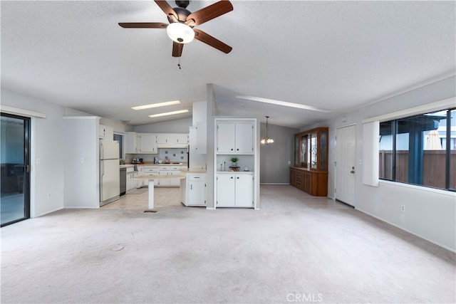 unfurnished living room with light colored carpet, a ceiling fan, vaulted ceiling, and baseboards
