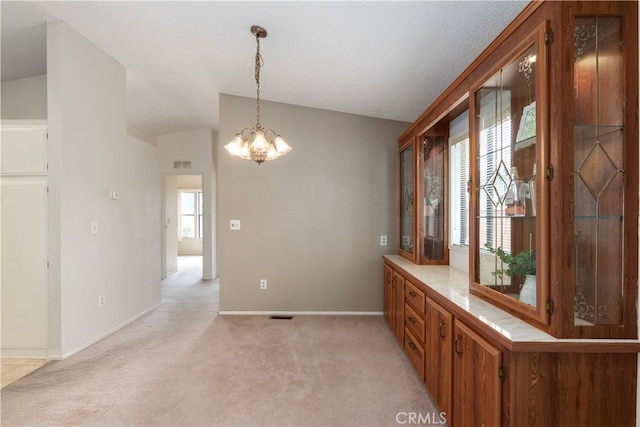 spare room featuring a chandelier, baseboards, visible vents, and light colored carpet