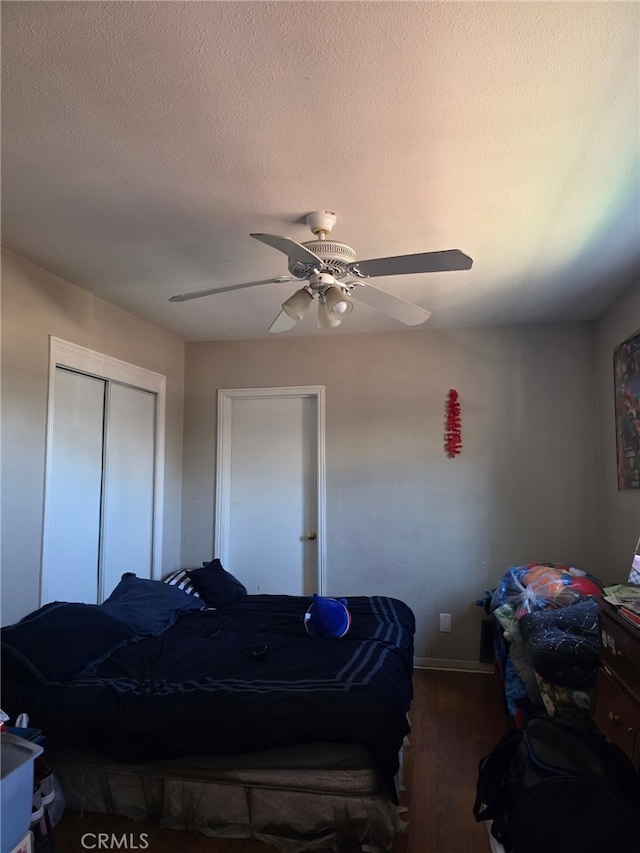 bedroom with a closet, a ceiling fan, baseboards, a textured ceiling, and wood finished floors