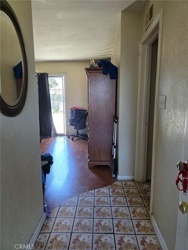 hallway featuring visible vents and a textured wall