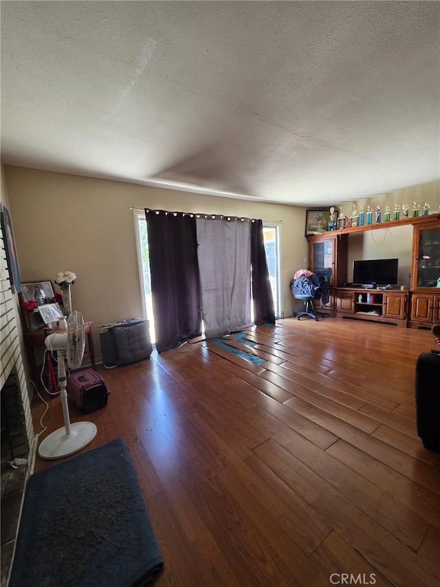 living room featuring wood finished floors, a brick fireplace, and plenty of natural light