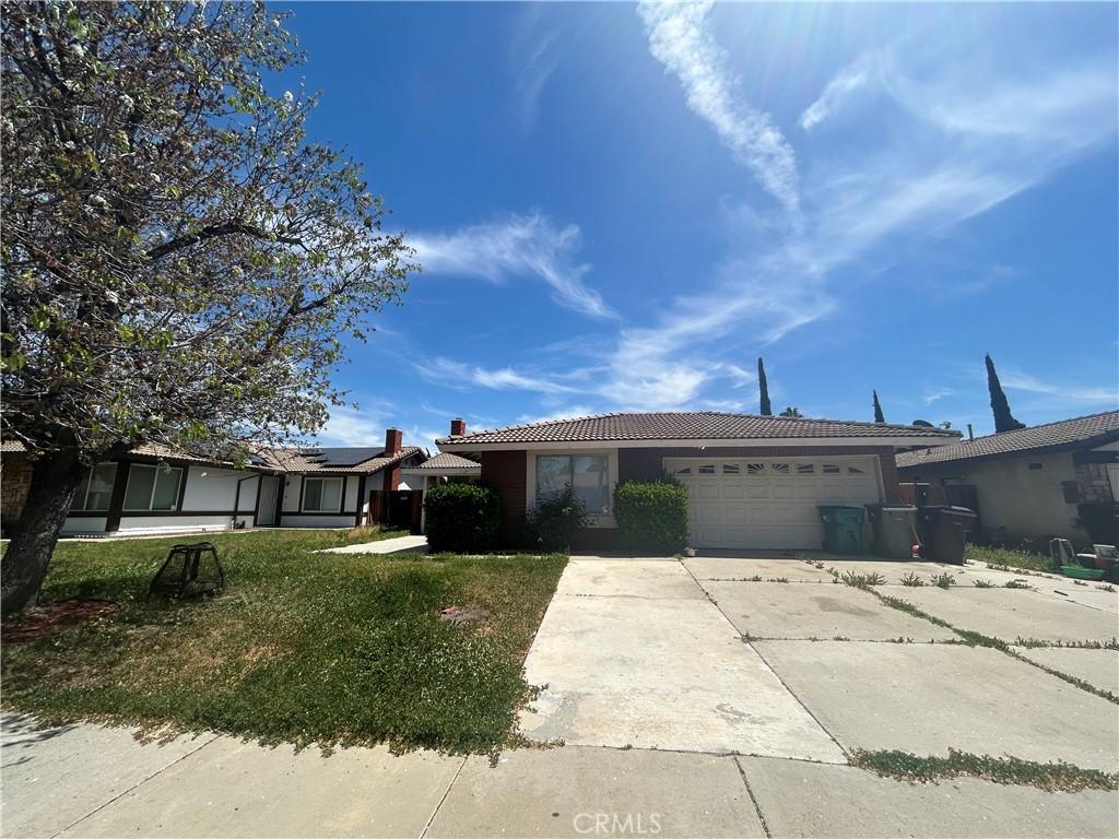 ranch-style house featuring stucco siding, a tile roof, driveway, and an attached garage