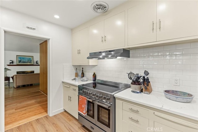 1273 E 7th St, Chico, CA 95928 - kitchen with range with two ovens, under cabinet range hood, light wood-style flooring, backsplash, and white cabinetry