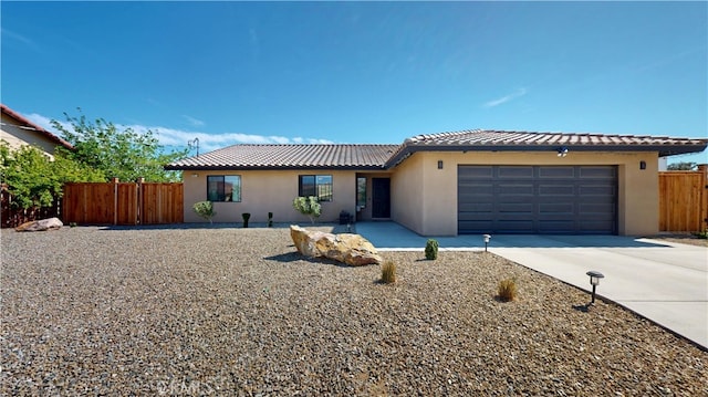 single story home with stucco siding, fence, a tile roof, concrete driveway, and an attached garage