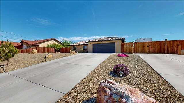 single story home featuring stucco siding, a tiled roof, concrete driveway, and fence private yard