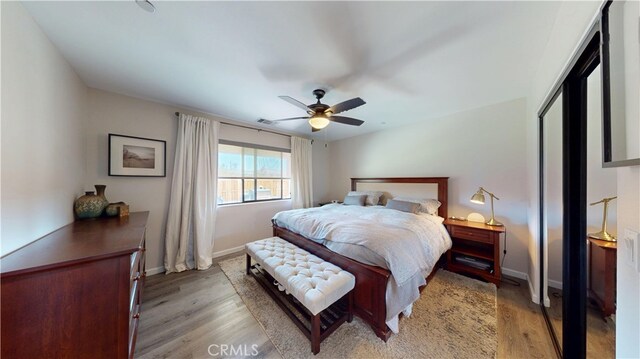 bedroom with wood finished floors, ceiling fan, visible vents, and baseboards