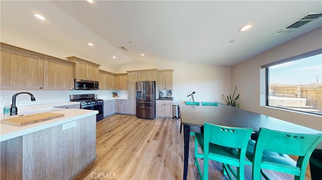 kitchen featuring light wood finished floors, visible vents, vaulted ceiling, light countertops, and appliances with stainless steel finishes
